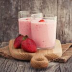 Fresh healthy strawberry smoothie on old wooden background