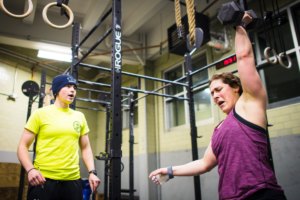 woman performs dumbbell shoulder workout in gym